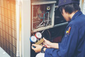 Technician repairing air conditioning unit with gauges