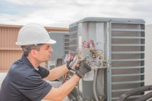 Technician repairing outdoor air conditioning unit wires