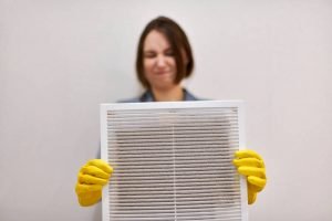 Person holding dirty air filter with gloves