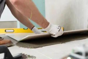 Worker installing floor tile with adhesive